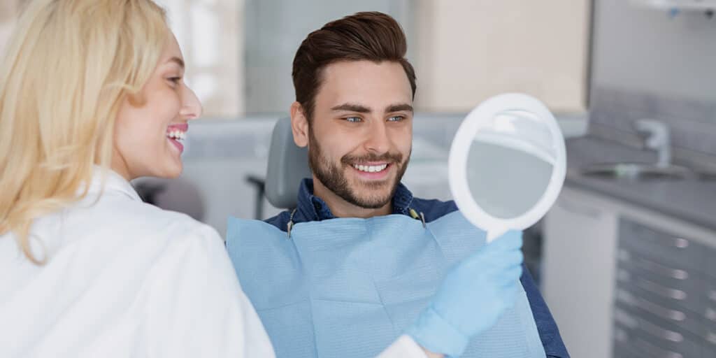 Man smiling in dentists chair after hygienist remove stains