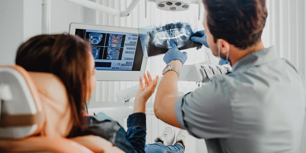 Dentist holding up x ray for what happens hygienist visit
