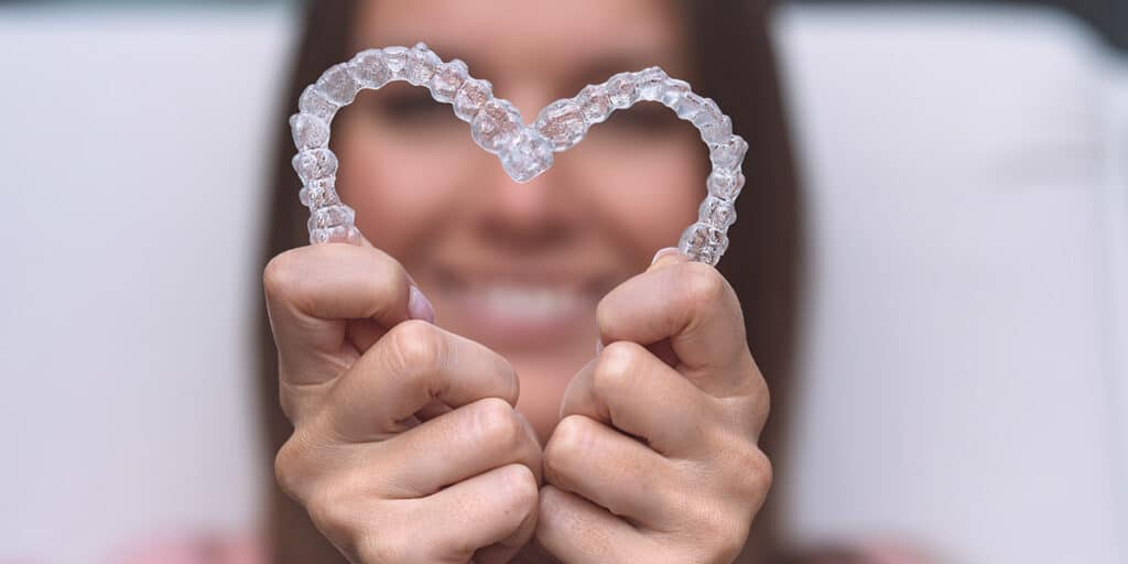 Woman holding complete set of invisalign clear aligners invisalign price differences